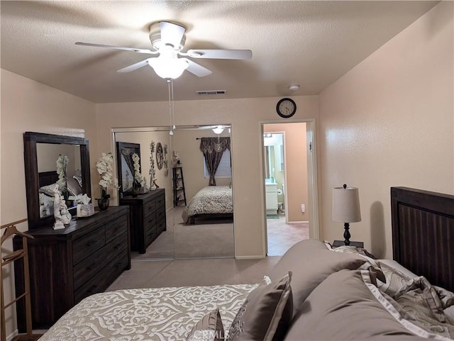 carpeted bedroom featuring ceiling fan, ensuite bathroom, a closet, and a textured ceiling