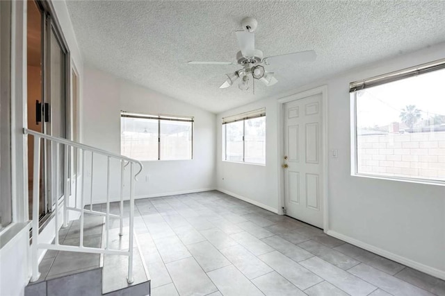 interior space featuring ceiling fan, lofted ceiling, and a textured ceiling