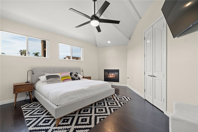 bedroom with ceiling fan, dark hardwood / wood-style flooring, vaulted ceiling, and a closet