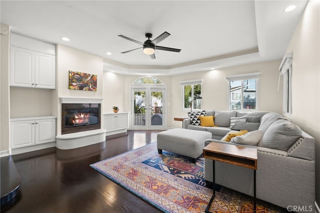 living room featuring dark hardwood / wood-style flooring, a raised ceiling, ceiling fan, and french doors