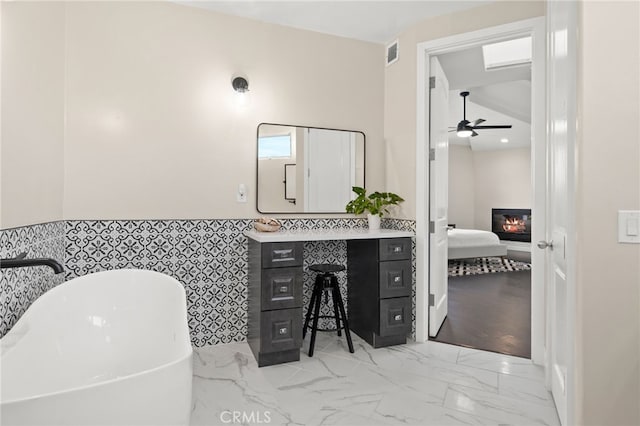 bathroom featuring tile walls, ceiling fan, vanity, and a bathing tub