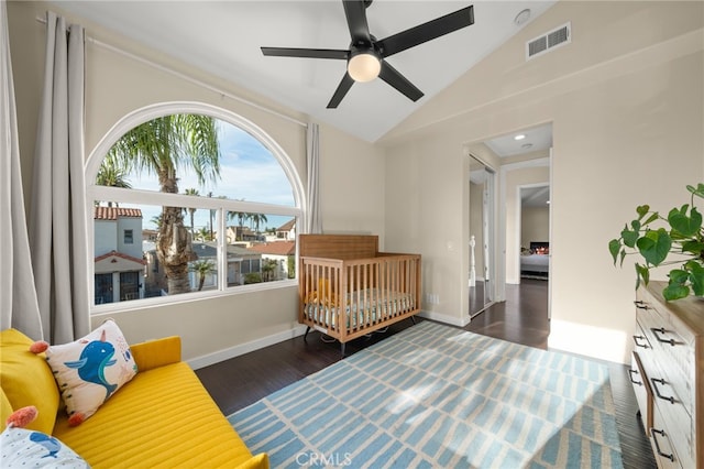 bedroom with a crib, lofted ceiling, dark hardwood / wood-style floors, and ceiling fan