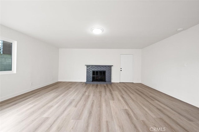 unfurnished living room featuring a brick fireplace and light hardwood / wood-style flooring