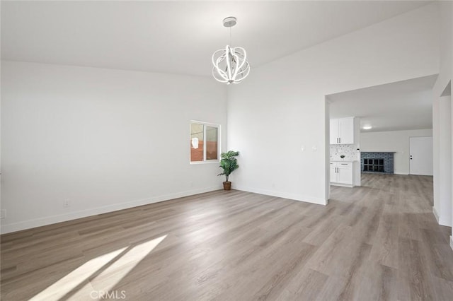 unfurnished room with a notable chandelier and light wood-type flooring