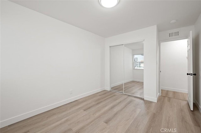 unfurnished bedroom with a closet and light wood-type flooring