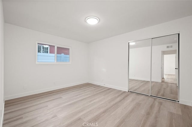 unfurnished bedroom with light hardwood / wood-style flooring and a closet