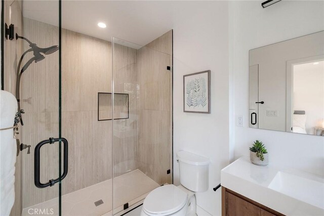 bathroom with a shower with door, vanity, and toilet