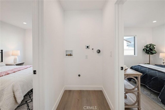 clothes washing area with hookup for a washing machine, gas dryer hookup, electric dryer hookup, and light hardwood / wood-style flooring