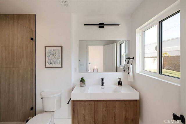 bathroom featuring vanity, toilet, and a healthy amount of sunlight