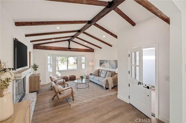 living room with a fireplace, light hardwood / wood-style flooring, and lofted ceiling with beams