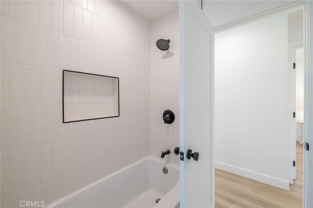 bathroom with hardwood / wood-style flooring and tiled shower / bath