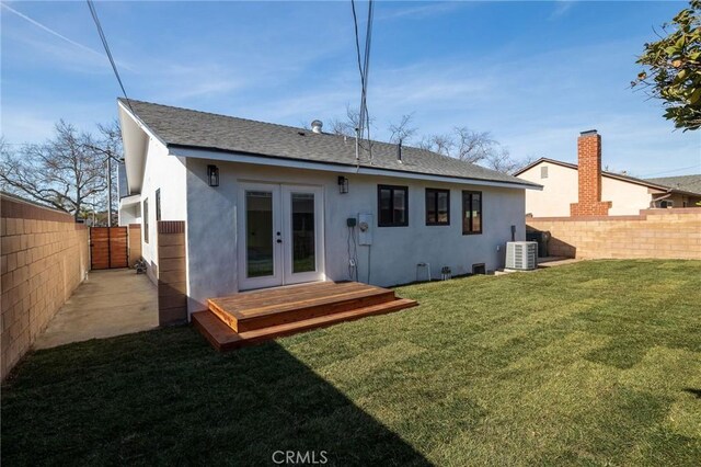 back of property with a lawn, french doors, and central air condition unit