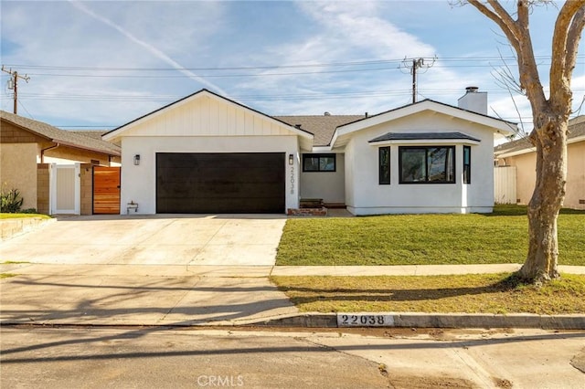 view of front of property with a chimney, concrete driveway, fence, a garage, and a front lawn