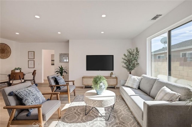 living room with light wood-style flooring, visible vents, baseboards, and recessed lighting