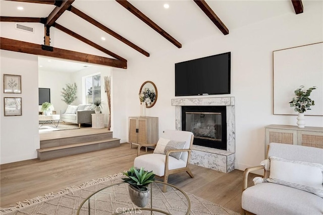 living area featuring vaulted ceiling with beams, recessed lighting, wood finished floors, visible vents, and a high end fireplace