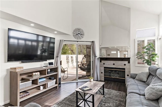 living room featuring wood-type flooring, high vaulted ceiling, and a tile fireplace