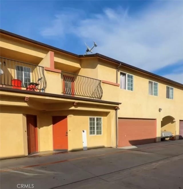 rear view of property featuring a balcony and a garage