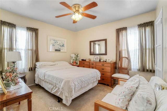 carpeted bedroom featuring multiple windows and ceiling fan