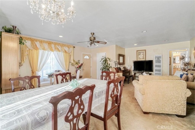 carpeted dining area featuring ceiling fan with notable chandelier