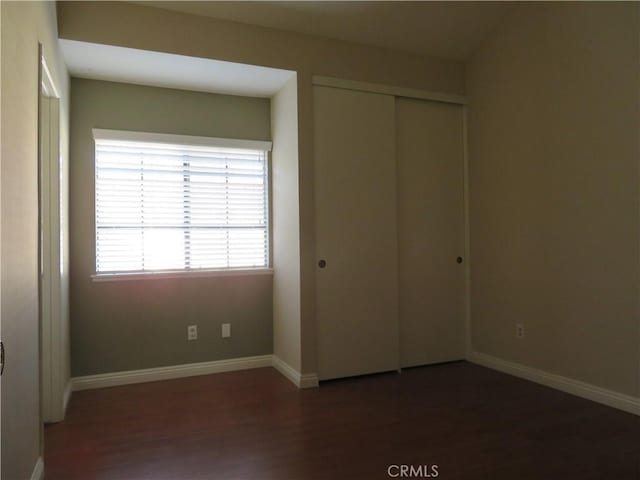 unfurnished bedroom featuring dark hardwood / wood-style floors and a closet