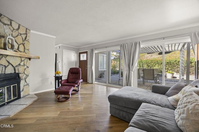 living room featuring wood-type flooring, ornamental molding, a textured ceiling, and a fireplace