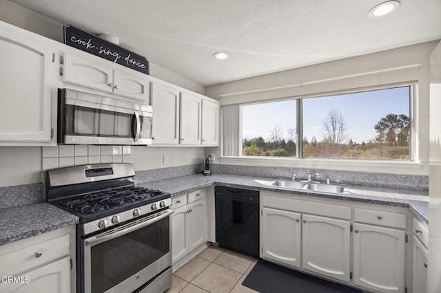 kitchen featuring sink, light tile patterned floors, stainless steel appliances, and white cabinets