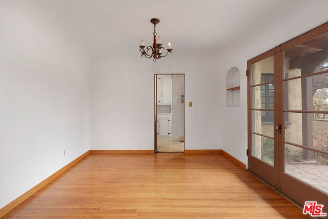 unfurnished room featuring an inviting chandelier and light hardwood / wood-style flooring