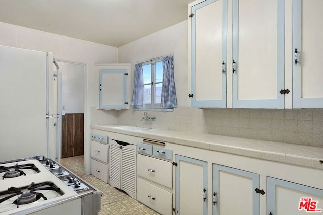 kitchen with white cabinetry, white fridge, sink, and backsplash