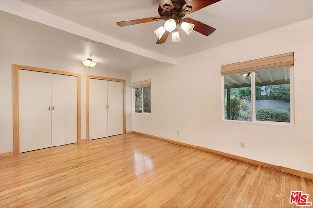 unfurnished bedroom with multiple windows, multiple closets, light hardwood / wood-style flooring, and ceiling fan