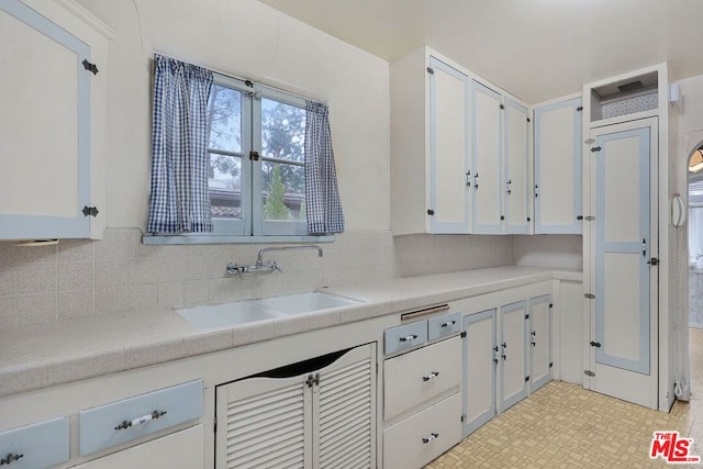 kitchen featuring white cabinetry, sink, and tasteful backsplash