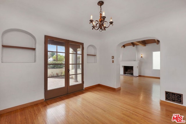 interior space featuring a notable chandelier, beam ceiling, light hardwood / wood-style floors, and french doors