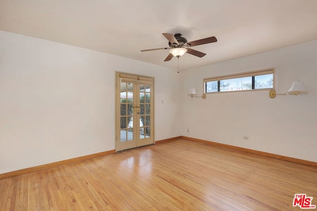 empty room with ceiling fan, light wood-type flooring, and french doors