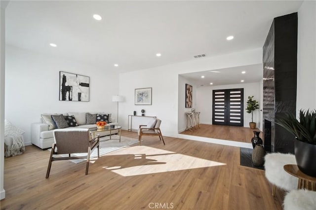 living room featuring a high end fireplace and light wood-type flooring