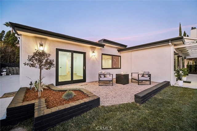 back house at dusk featuring a yard and a patio