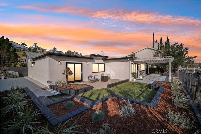 back house at dusk with a pergola and a patio