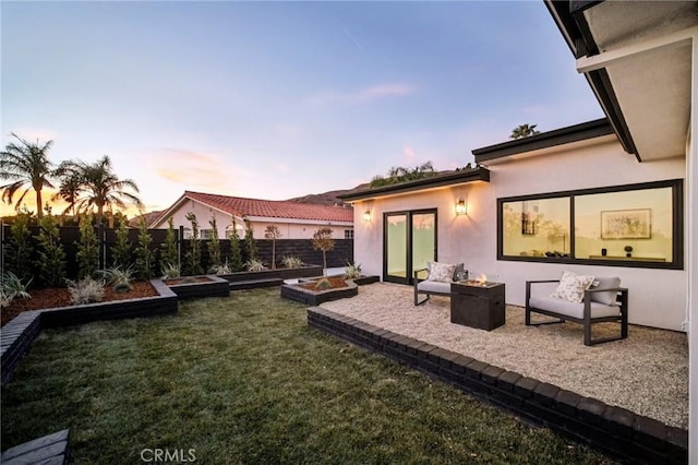 back house at dusk with a patio and a lawn