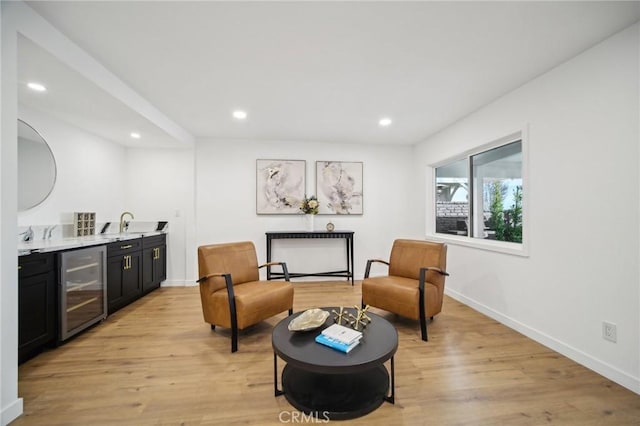 living area with wine cooler, wet bar, and light wood-type flooring