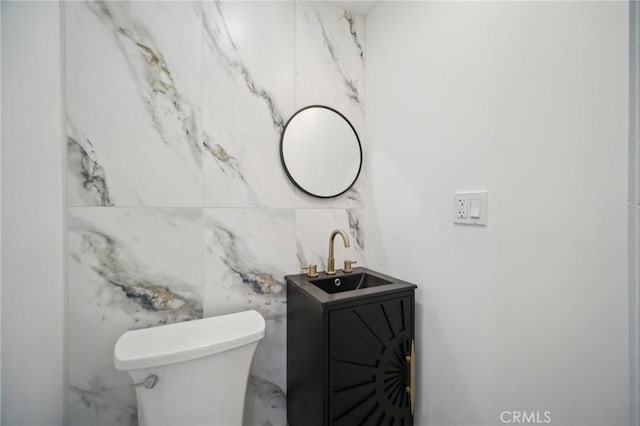 bathroom featuring vanity, tile walls, and toilet