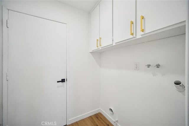 washroom with cabinets, washer hookup, and light hardwood / wood-style floors