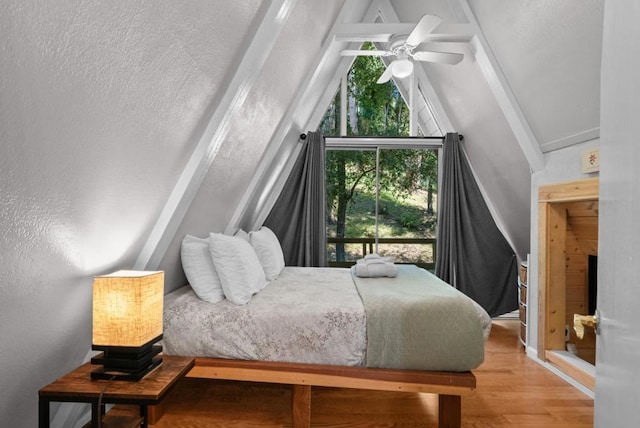 bedroom featuring vaulted ceiling with beams, a textured ceiling, ceiling fan, and light wood-type flooring