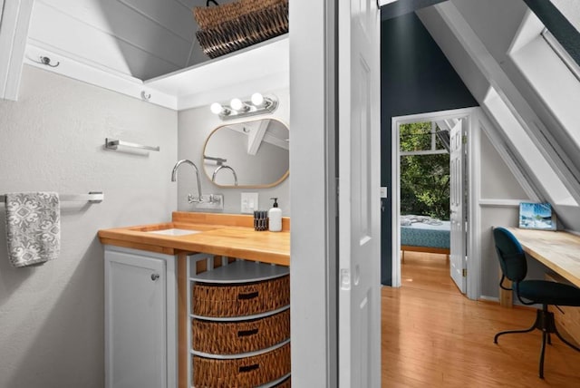 bathroom with hardwood / wood-style flooring, lofted ceiling, and vanity