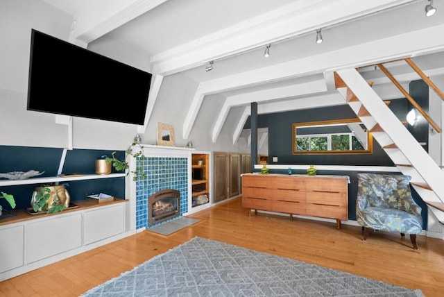 interior space with wood-type flooring, a tile fireplace, and lofted ceiling with beams