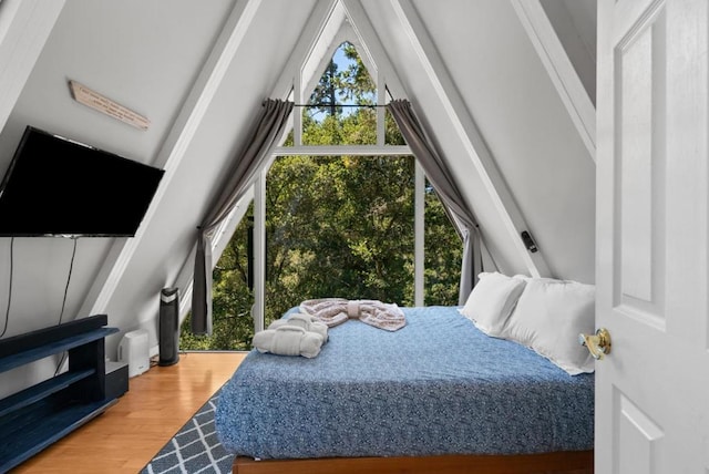 bedroom featuring hardwood / wood-style flooring, vaulted ceiling, and multiple windows