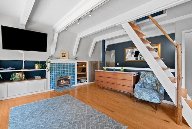 interior space featuring vaulted ceiling with beams, a fireplace, wood-type flooring, and track lighting