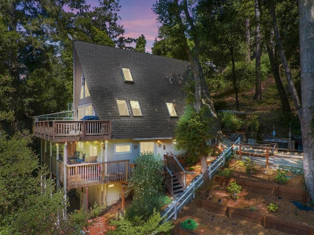 back house at dusk featuring a deck