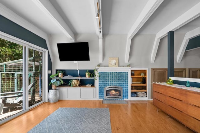 living room with beamed ceiling, rail lighting, a tiled fireplace, and hardwood / wood-style floors