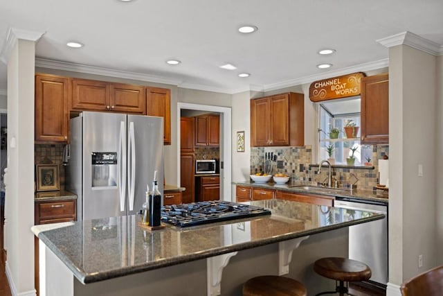 kitchen with sink, a kitchen island, dark stone counters, and appliances with stainless steel finishes