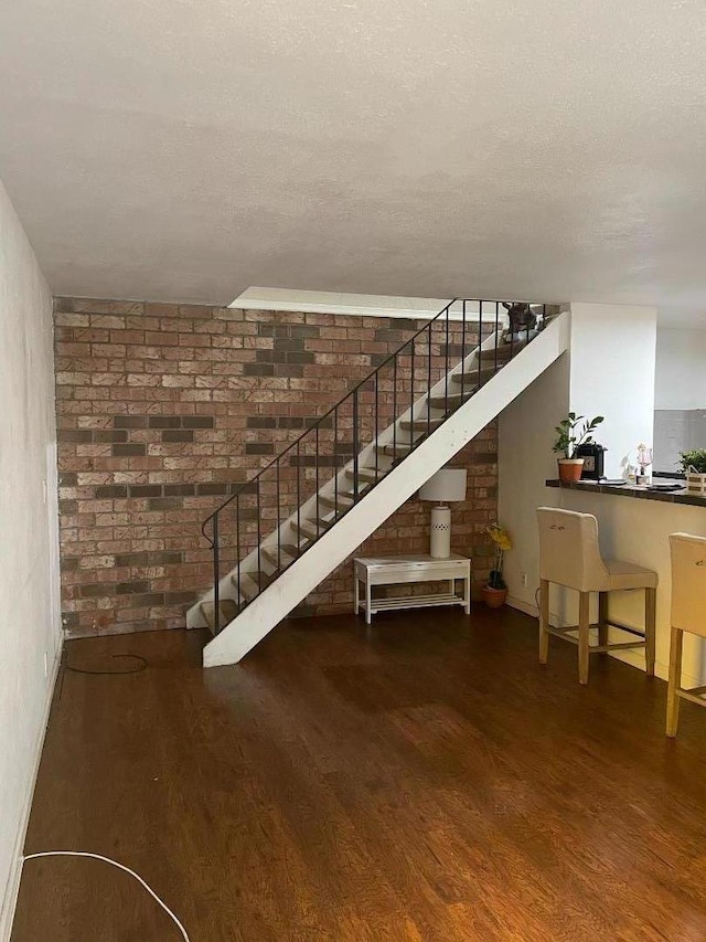 interior space with hardwood / wood-style flooring, brick wall, and a textured ceiling