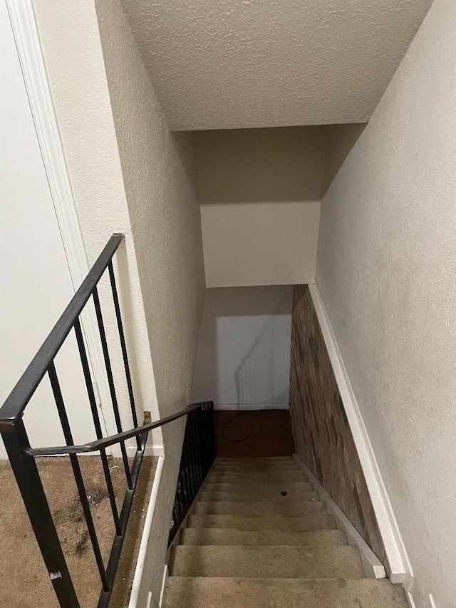 staircase featuring a textured ceiling