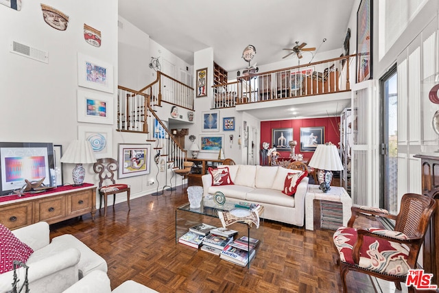 living room featuring ceiling fan, a towering ceiling, and dark parquet floors